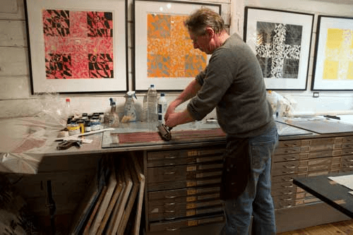 The artist rolling paint to press some new paintings